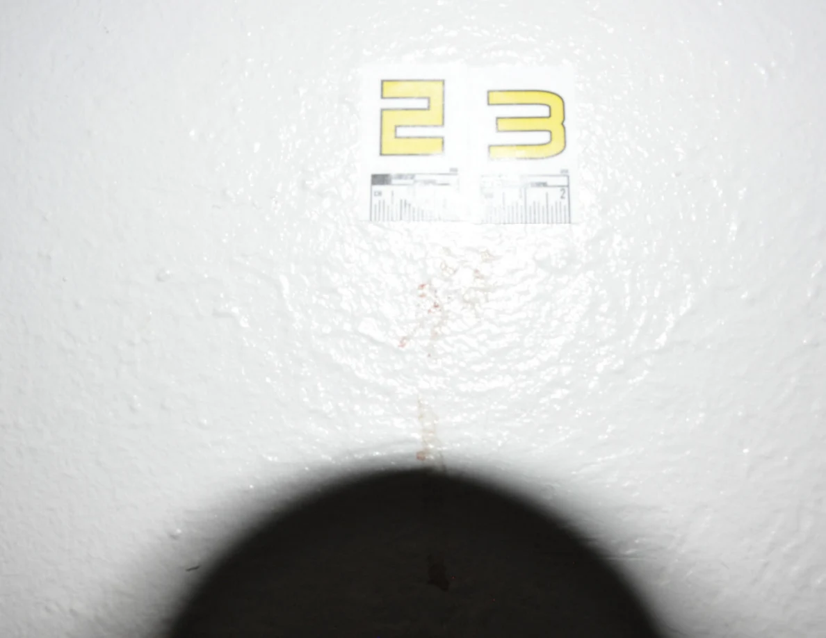 Bright close view of label 23 and reddish wall mark, with a shadow at the lower edge.