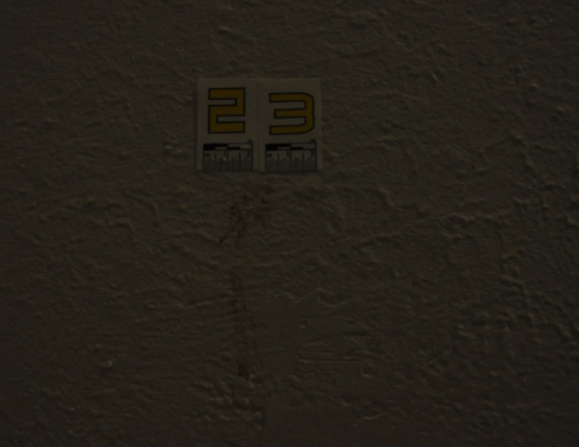Dim close view of label 23 above a reddish mark on textured wall.