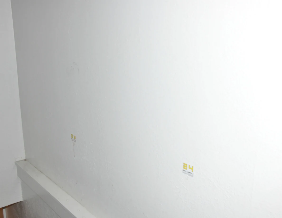Pale stairwell wall with small yellow labels 23 and 24 above white trim.