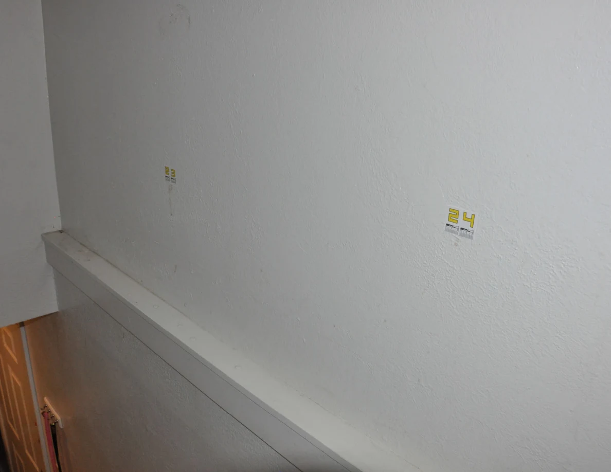 Dimmer view of labeled marks 23 and 24 above stairwell trim.