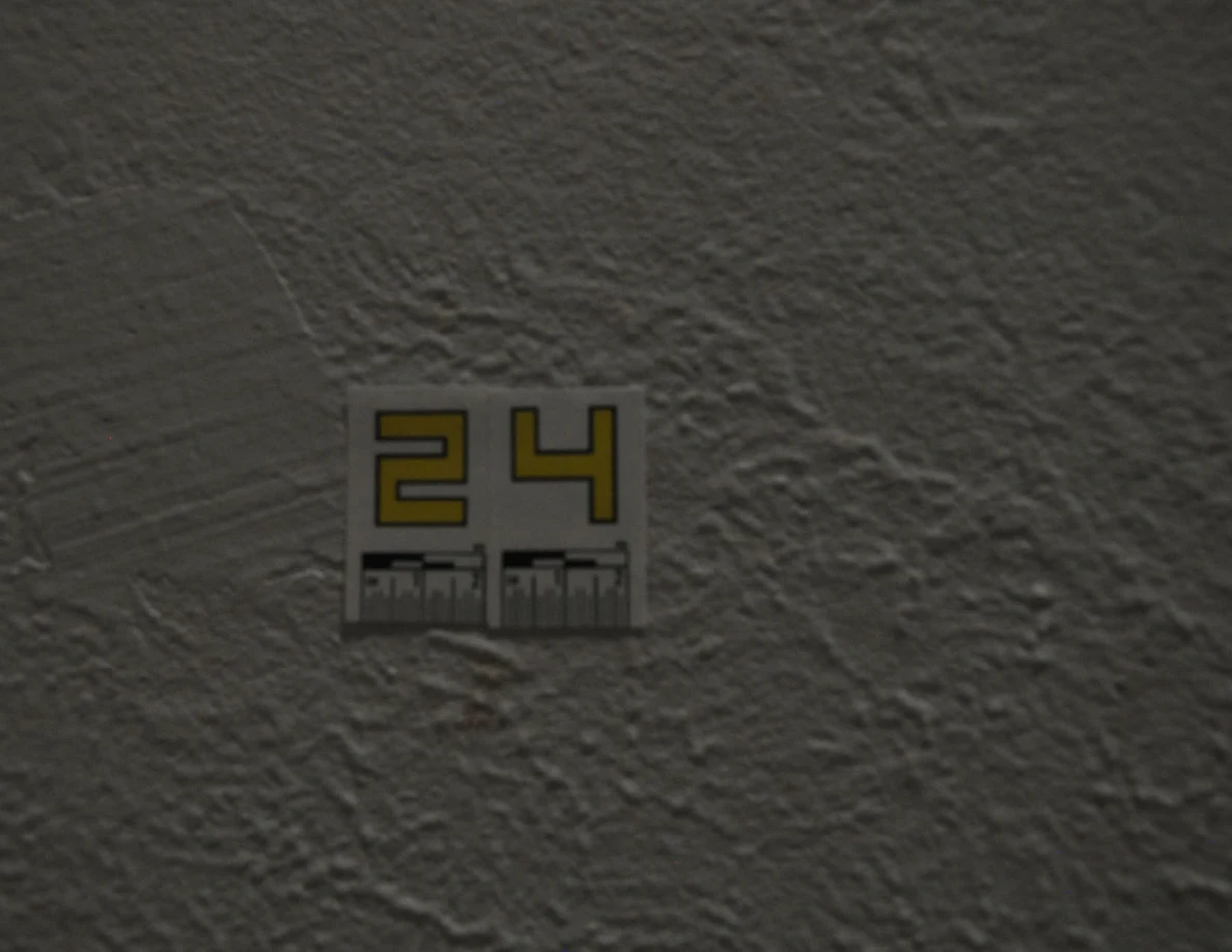Close view of yellow label 24 on textured paint with faint marks below.