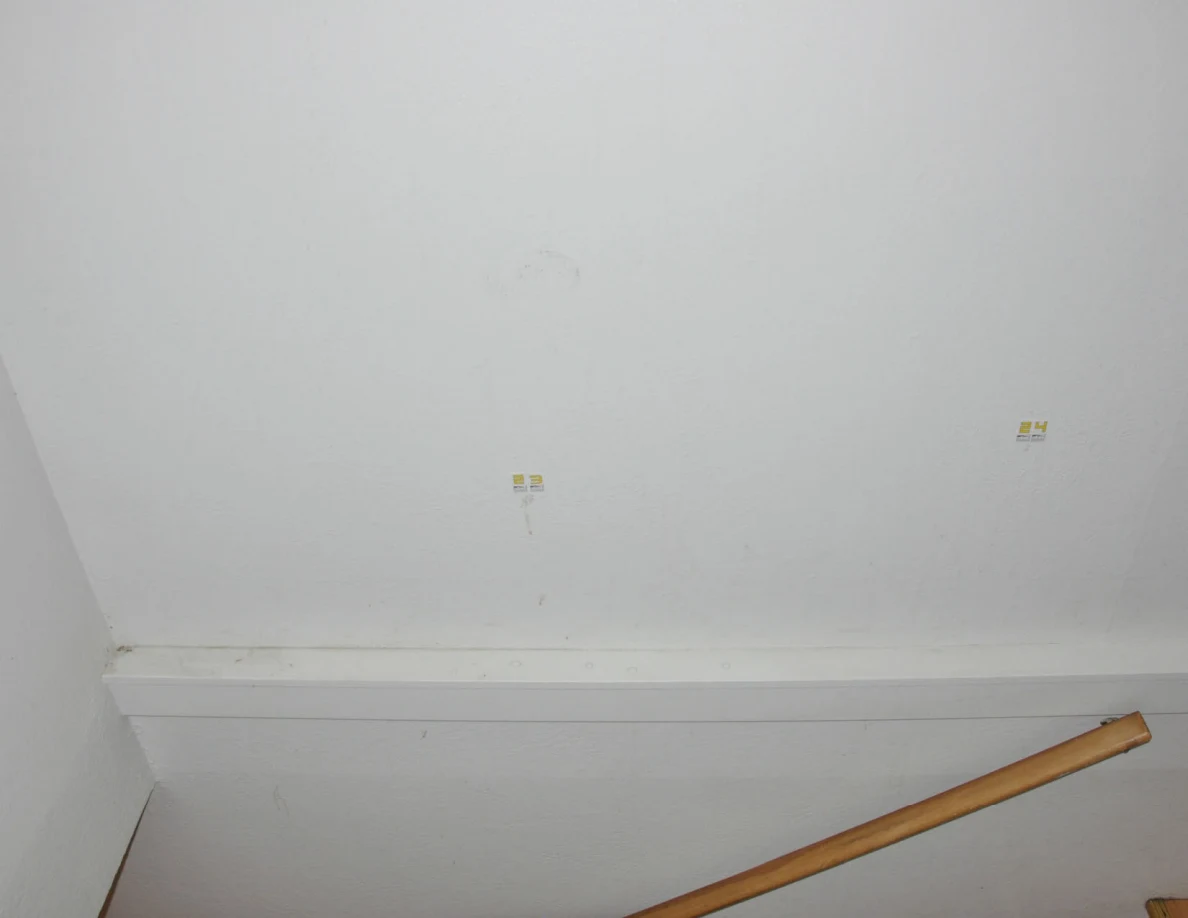 Wider stairwell wall with labels 23 and 24 above white trim and wooden handrail.