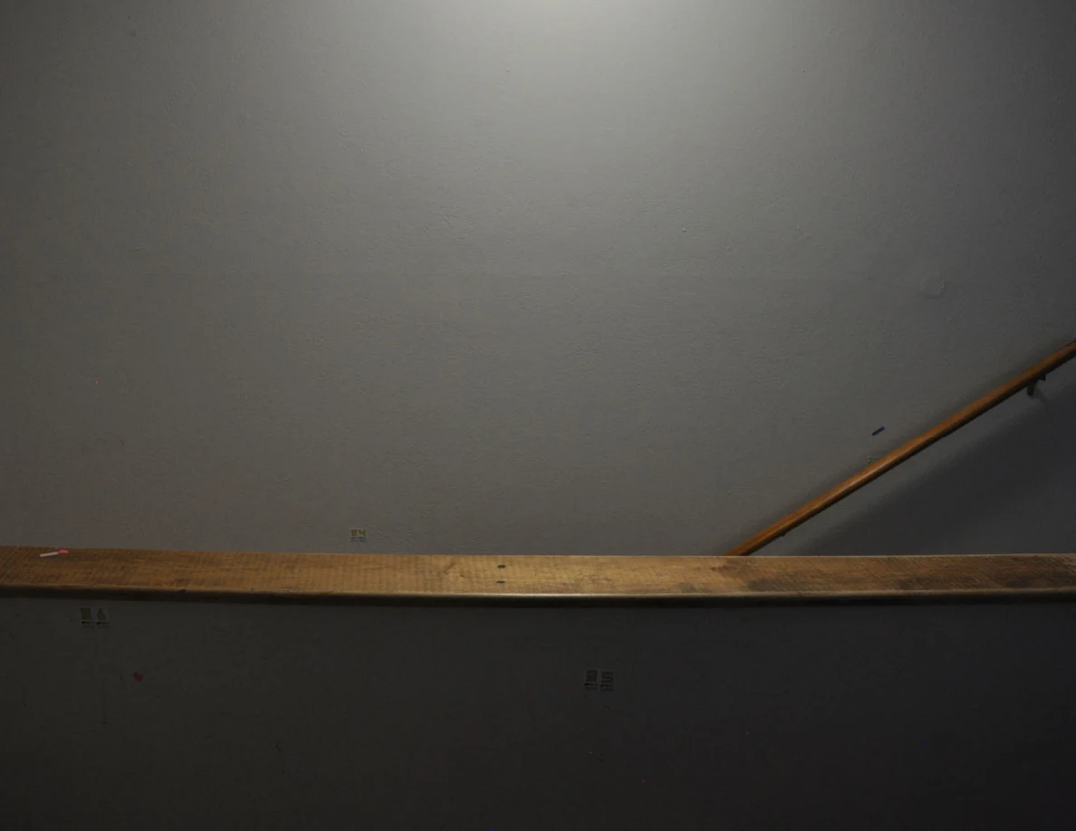 Darker view of a wood-capped half-wall and labeled stairwell wall.