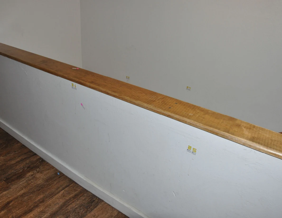 Angled view of a wood-capped half-wall with small yellow labels and pink tape.