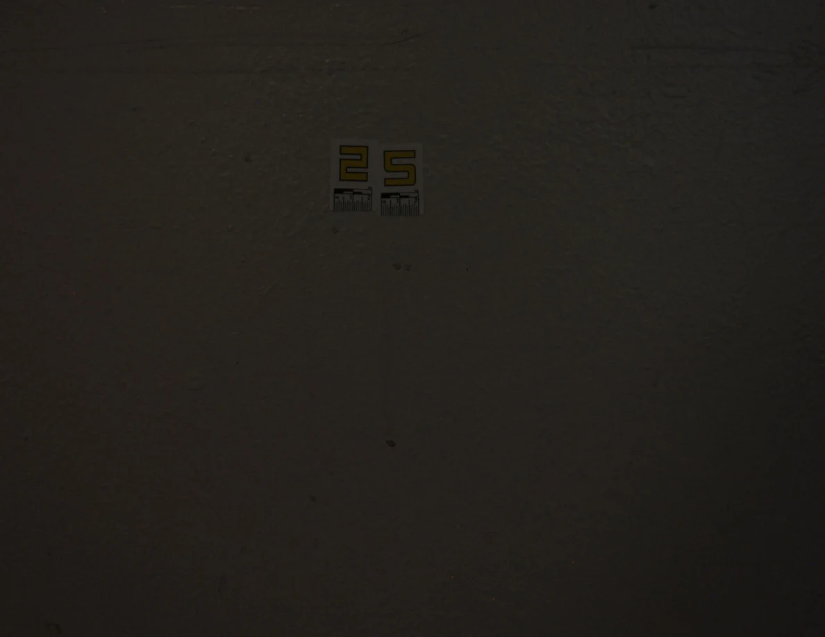 Dim view of label 25 and small spots on a pale wall.