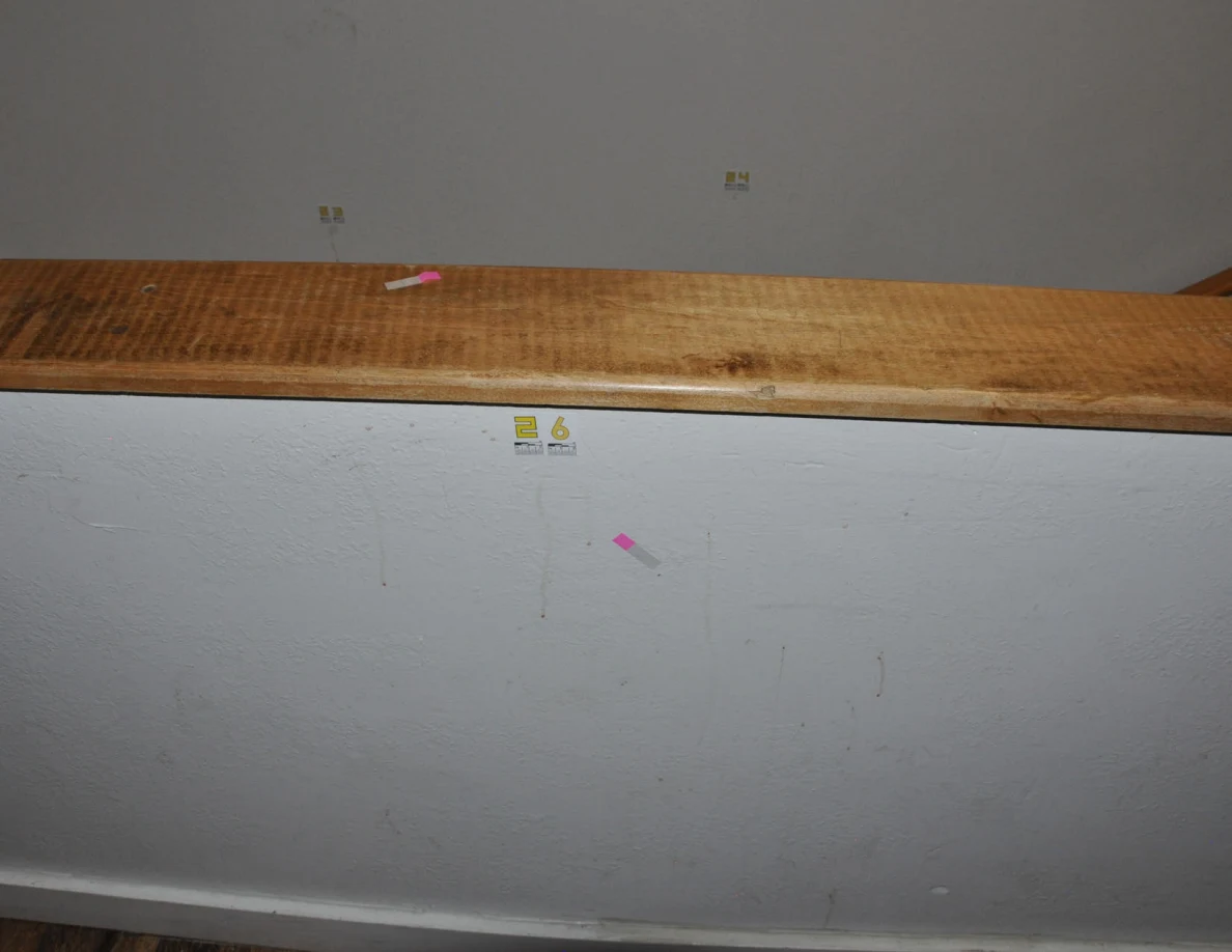 Wood-capped half-wall with label 26 and a pink tape square.