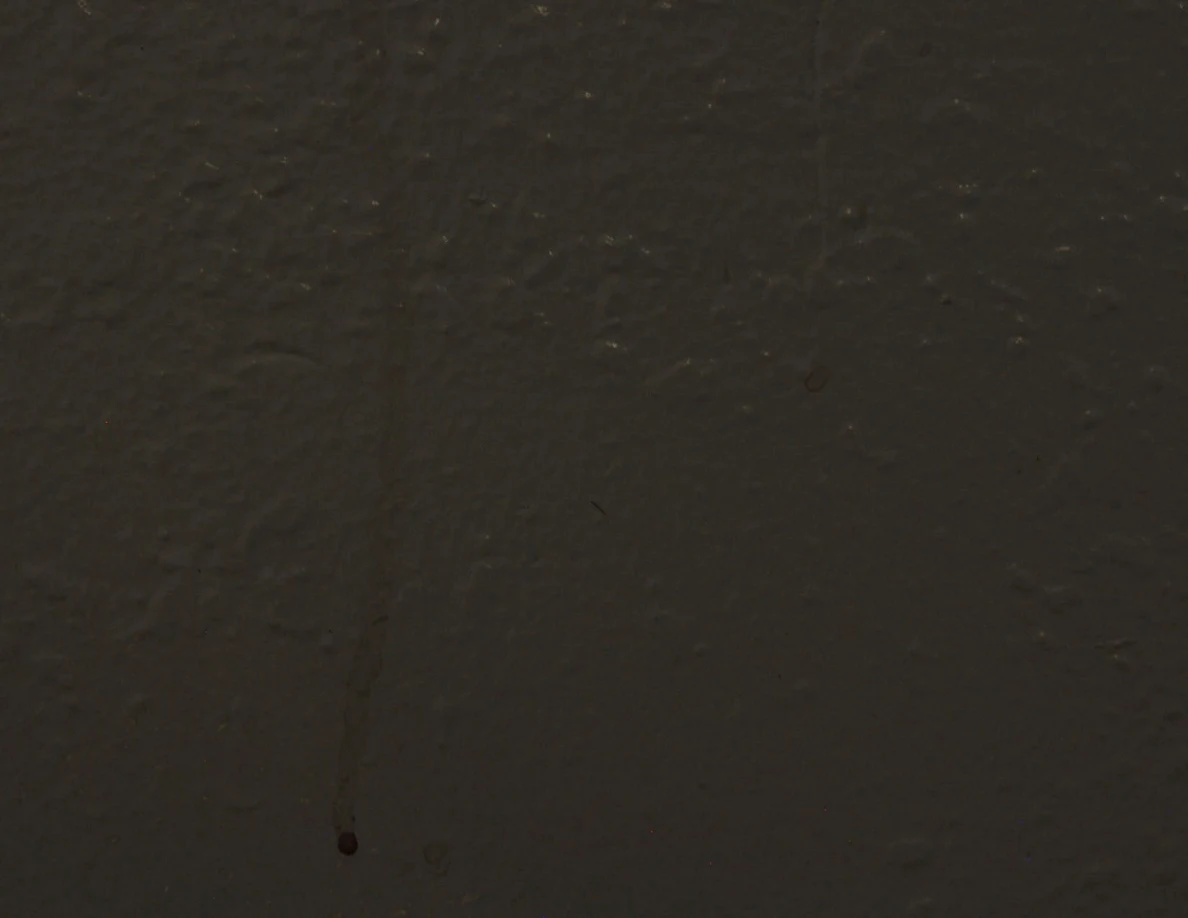 Close view of a faint reddish wall streak under subdued lighting.