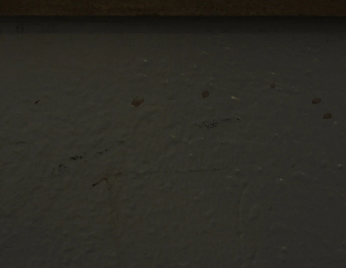 Reddish spots and dark scuffs on a wall beneath a wooden cap.