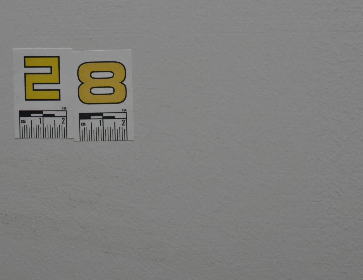 Yellow label 28 above a long faint curved mark on a pale wall.