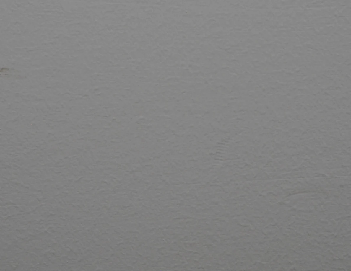 Closer view of the textured paint and faint curved wall scuff.