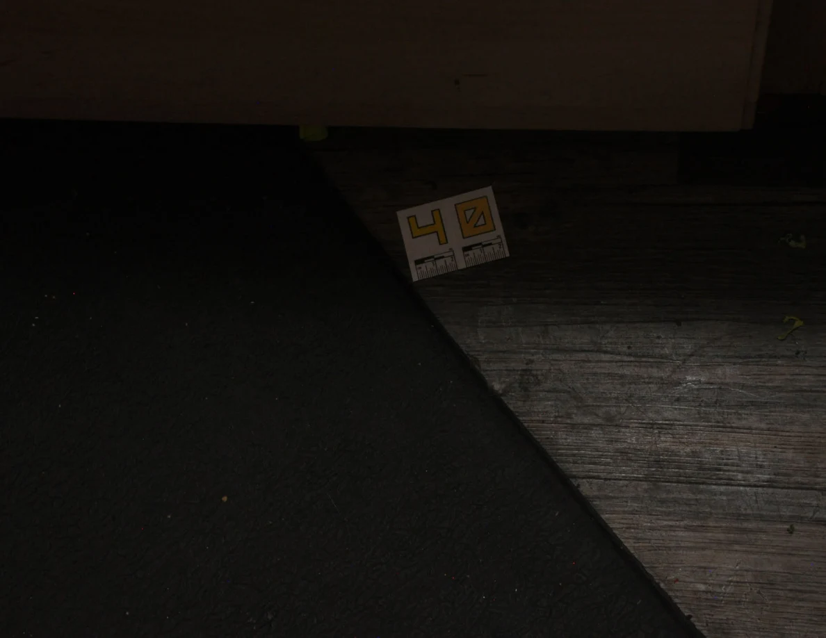 Dim view of label 40 on wood-look flooring beside a dark mat.