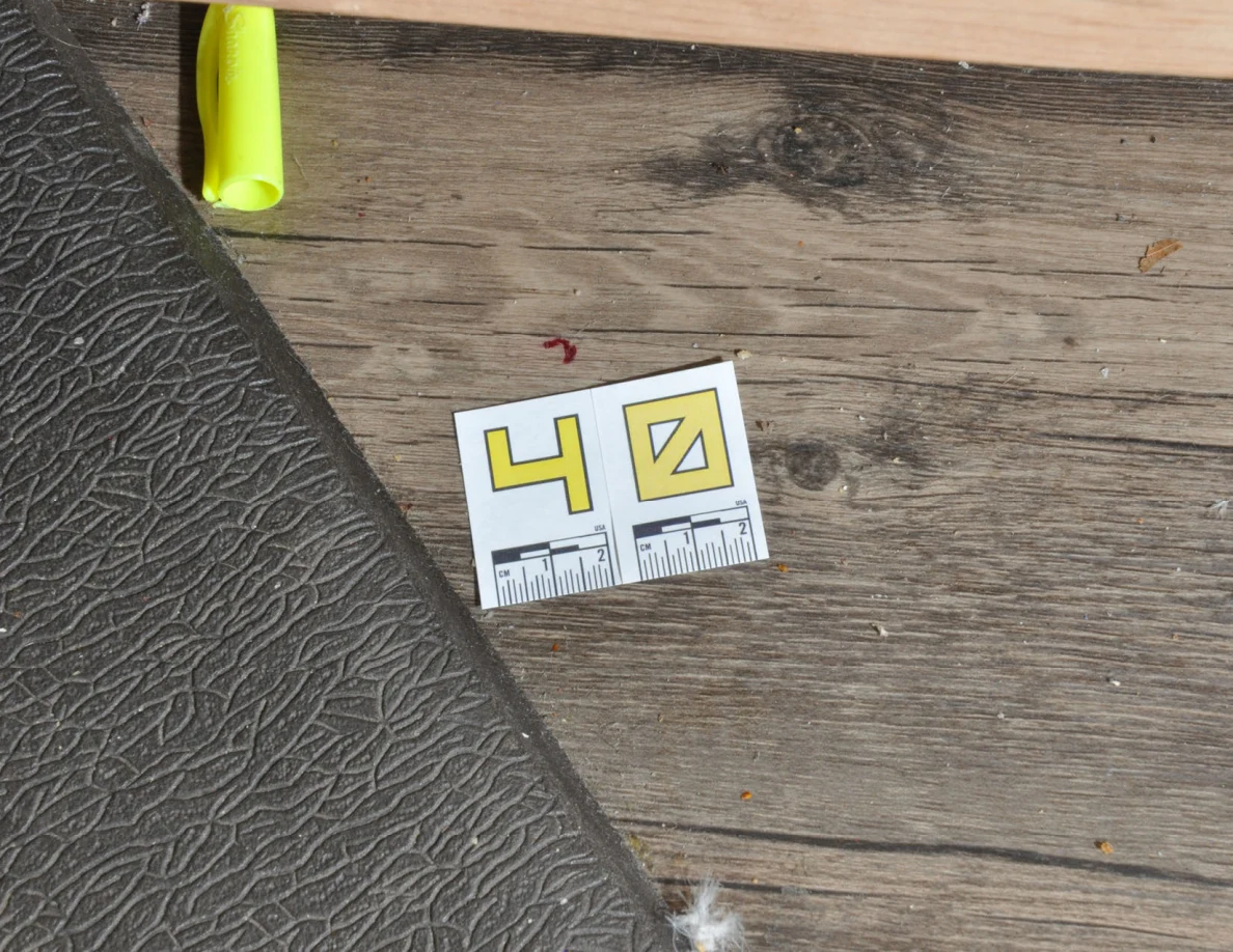 Close view of label 40 near a small reddish floor mark and green plastic item.