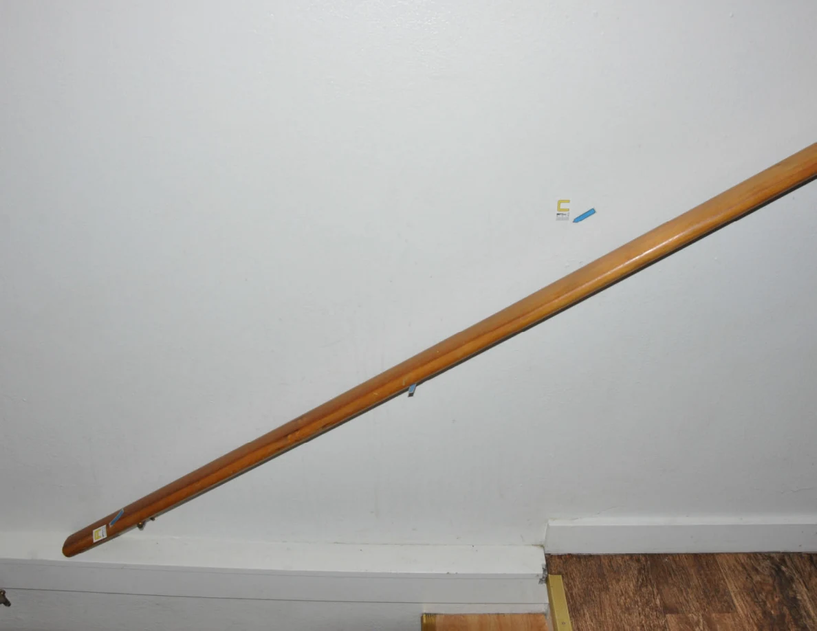 Long wooden handrail beside a wall bearing letter label C and a blue arrow.