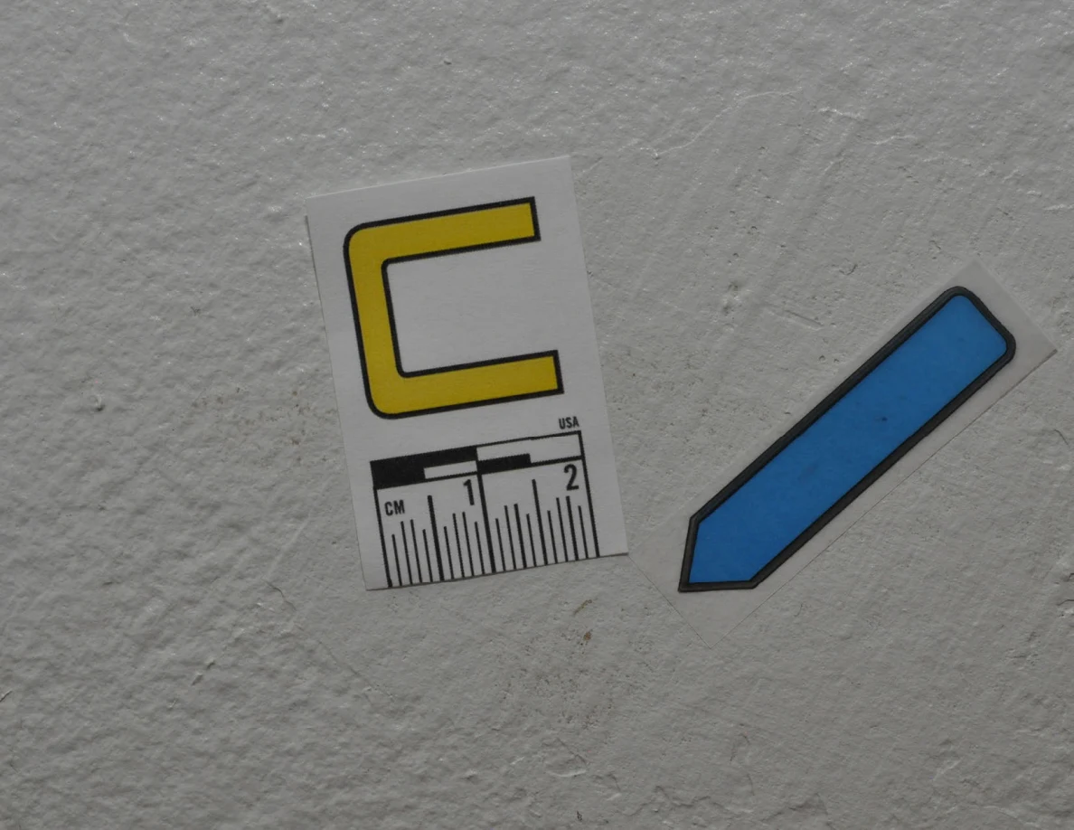 Close view of label C and blue arrow on pale textured paint.