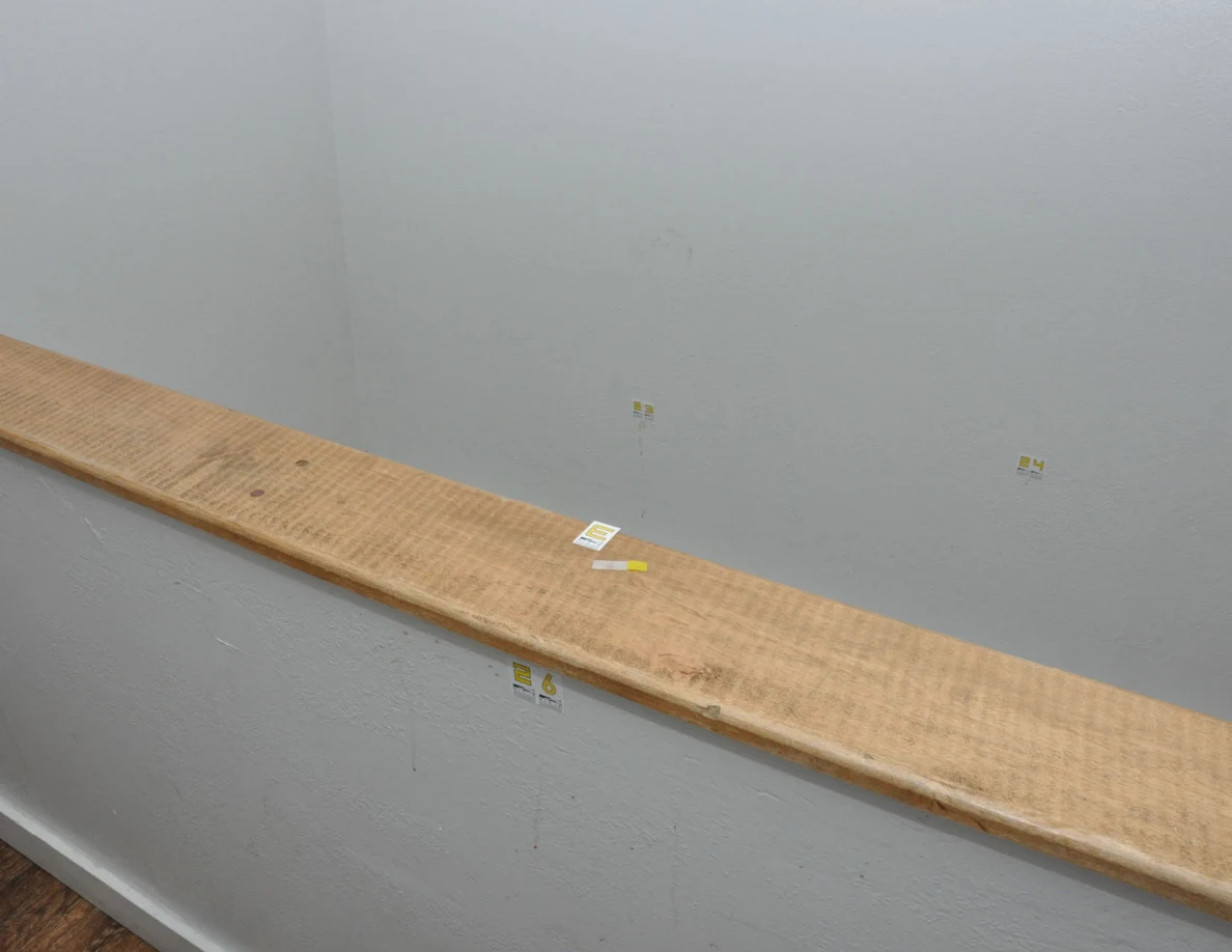Wood-capped half-wall with small labels and yellow tape beside stairwell walls.