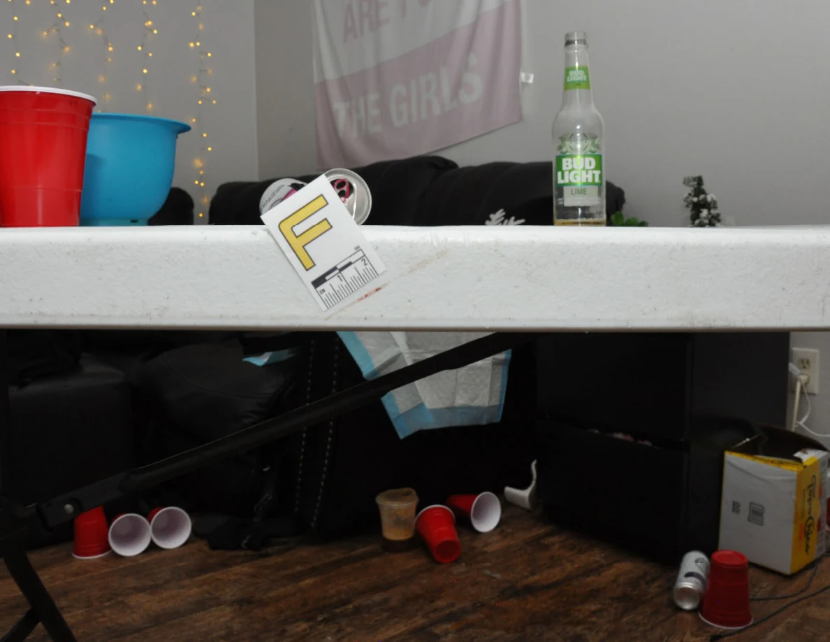 White folding-table edge bearing label F, with cups and clear bottle on top.