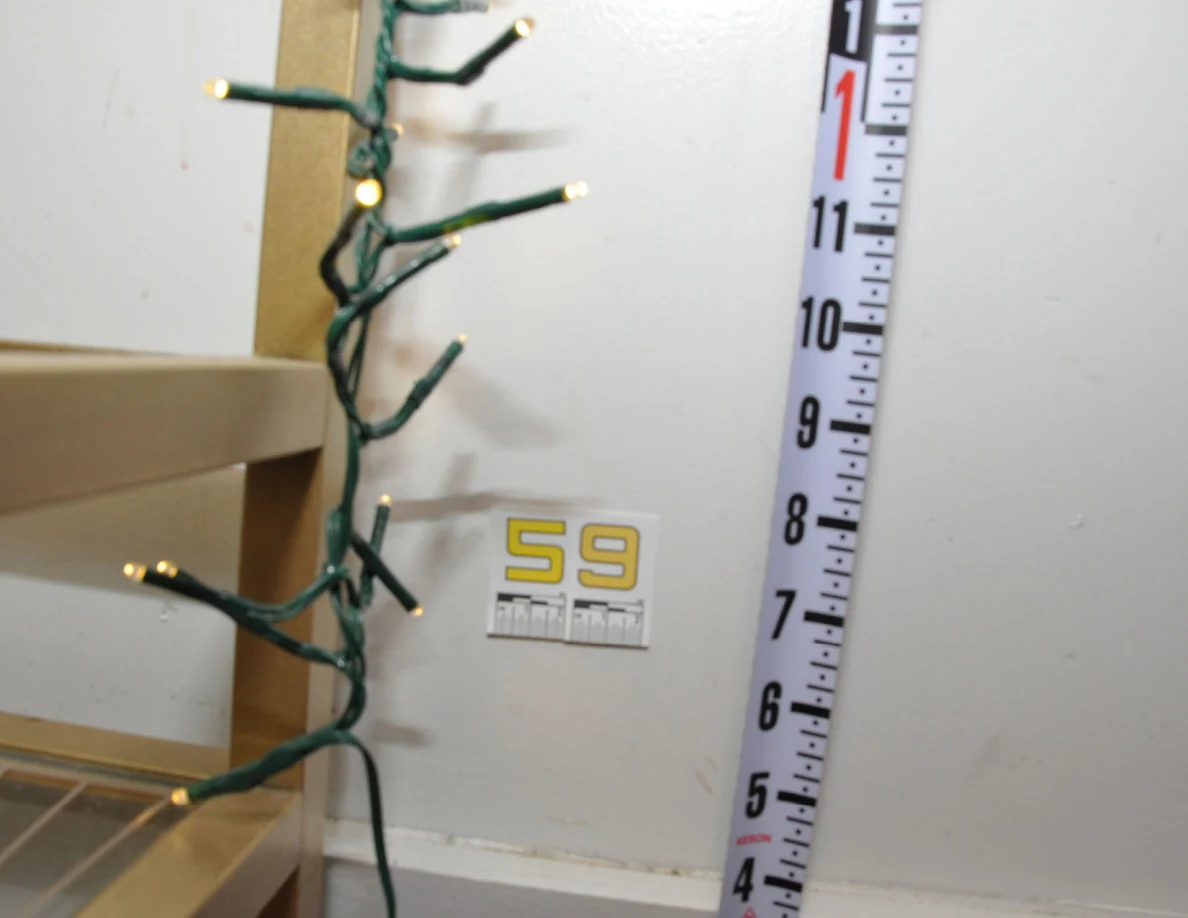 Yellow label 59 beside a vertical measuring tape and serving-cart string lights.