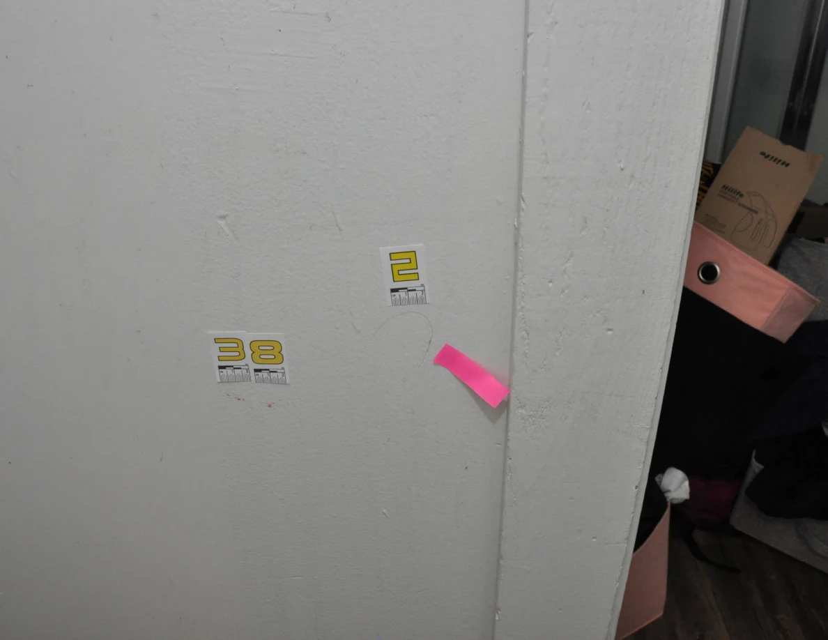 Wall beside doorway with label 38, label 2, curved strand and pink tape.