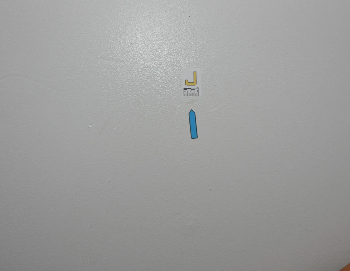 Letter label J and a blue arrow on a pale stairwell wall.