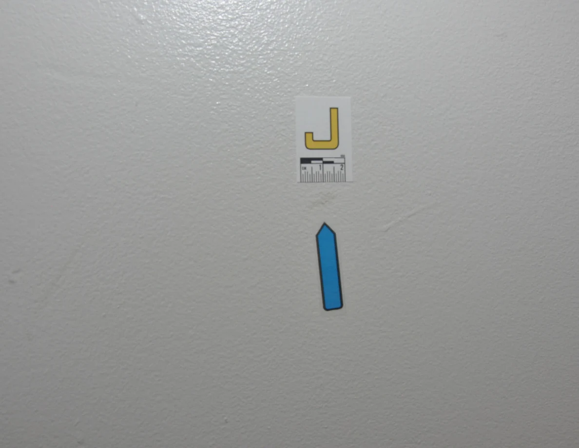 Closer view of label J and blue arrow beneath faint wall marks.