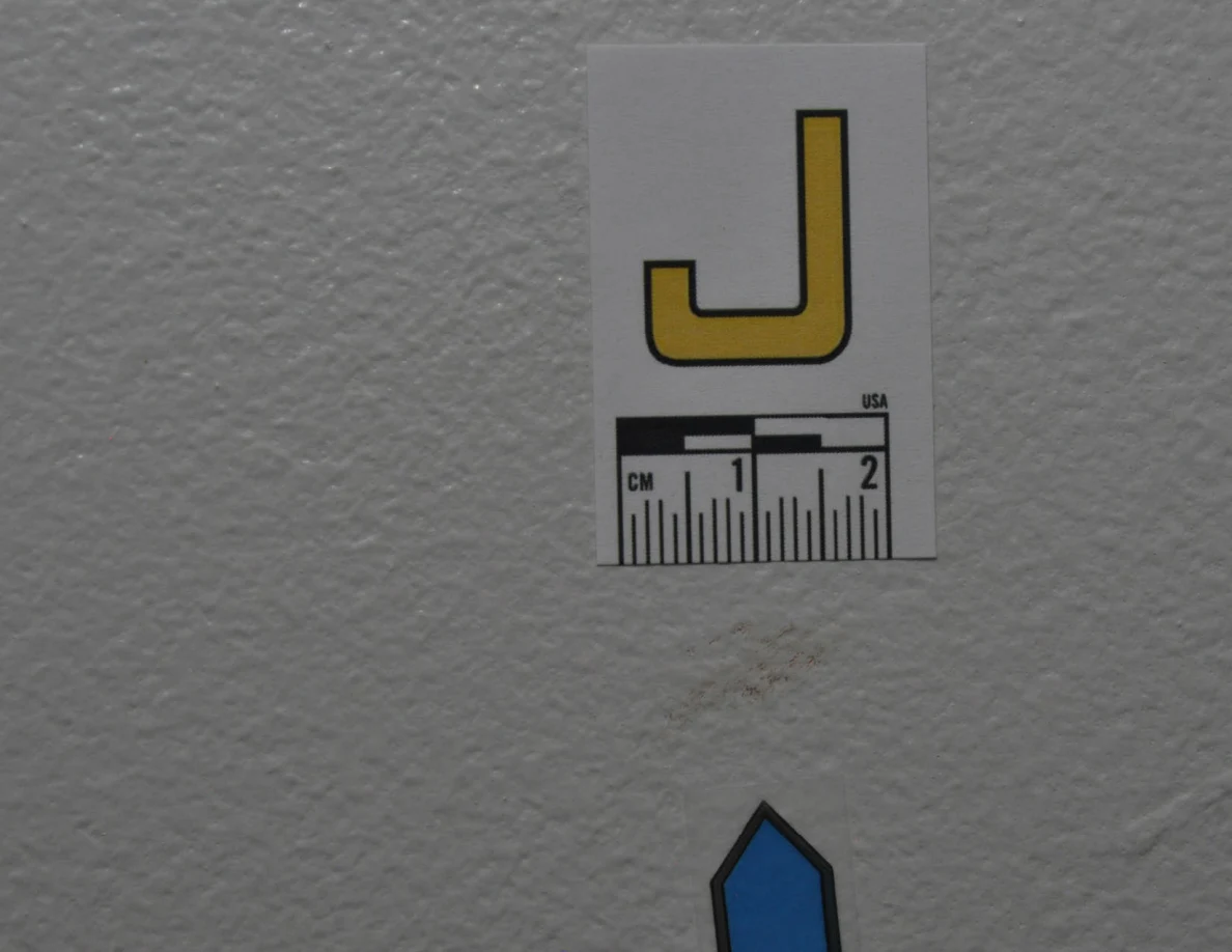 Close view of label J and faint marks on textured paint.
