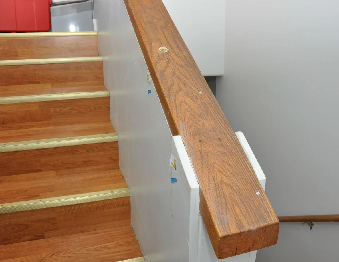 Wooden stair cap and half-wall with small labels and blue arrows.