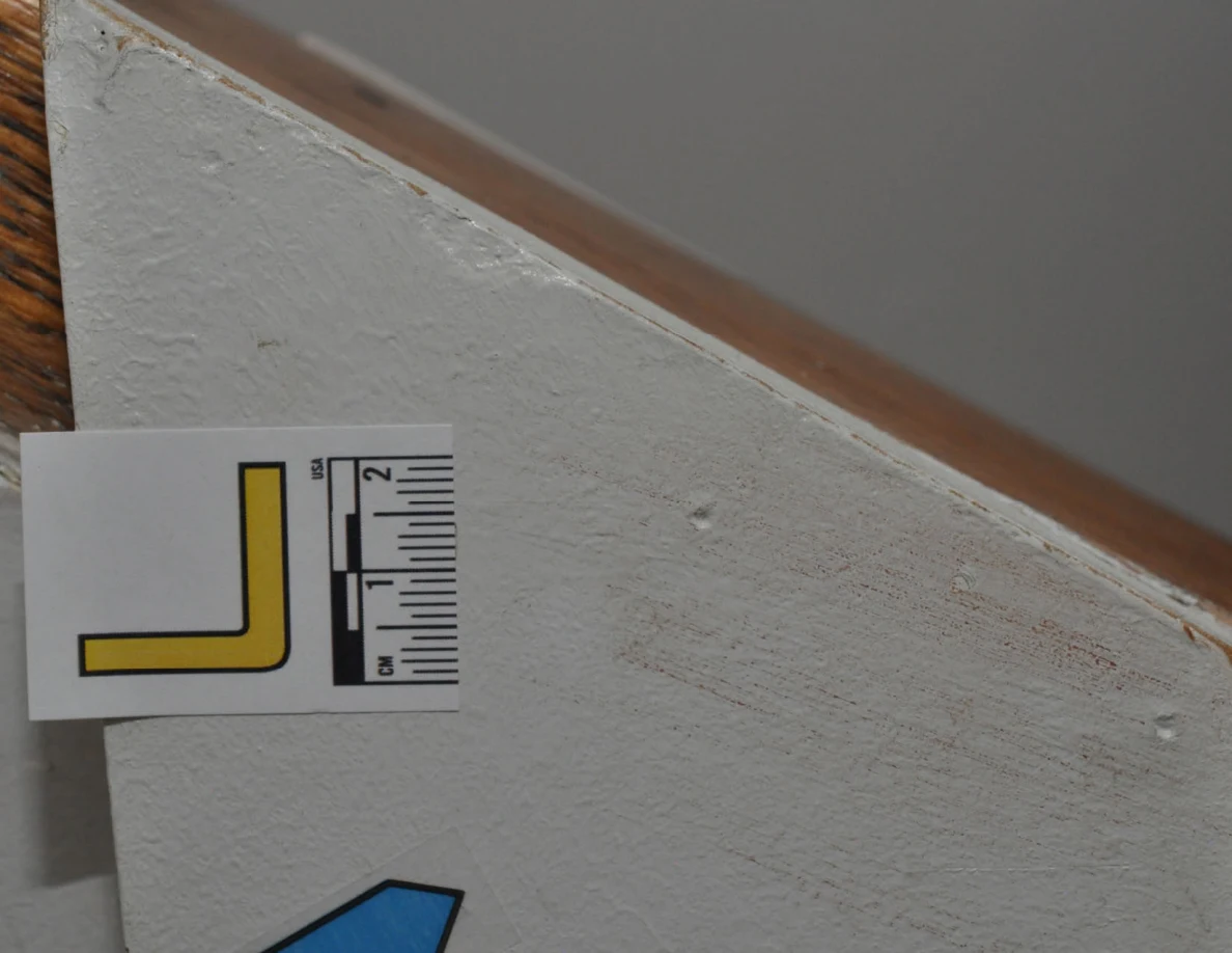 Close view of label L and blue arrow near the sloping edge of a half-wall.