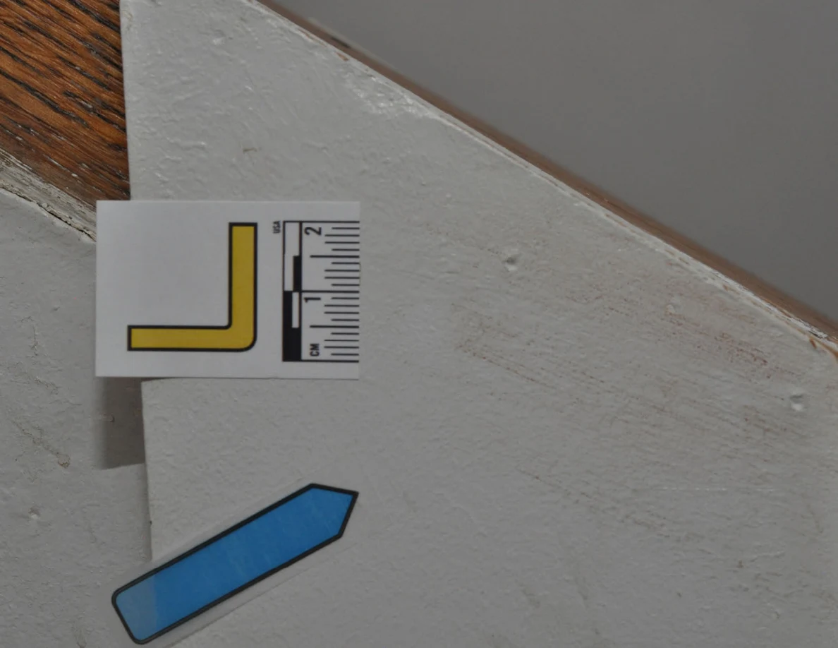Label L and blue arrow beside faint marks beneath a wooden cap.