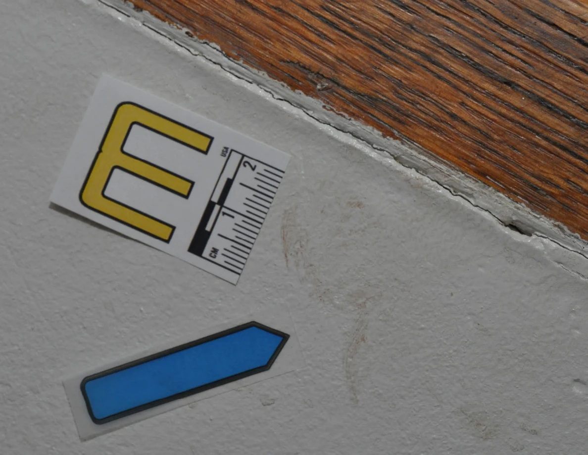 Letter label M and blue arrow beside faint vertical marks below a wooden cap.