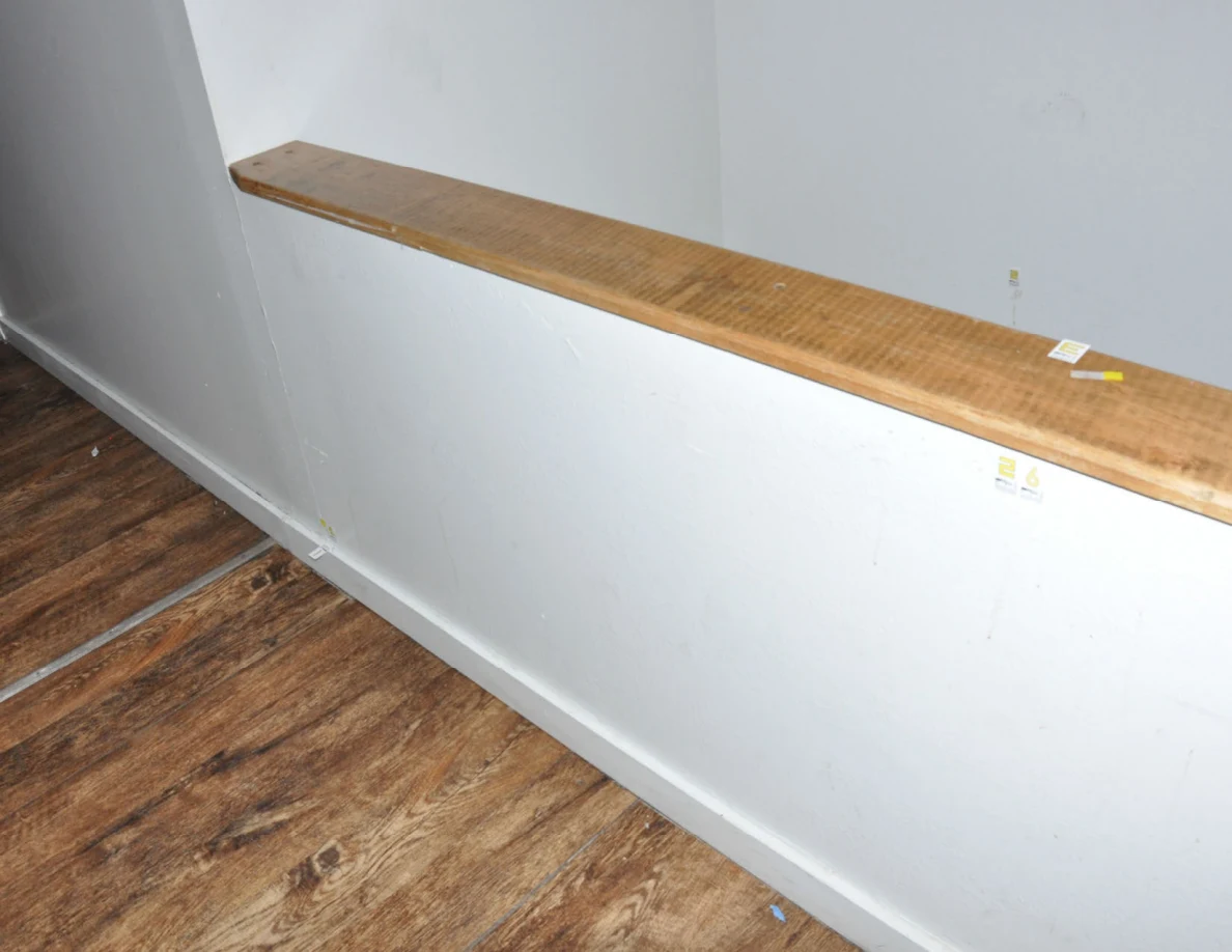 Angled view along a wood-capped half-wall with faint streaks and small labels.