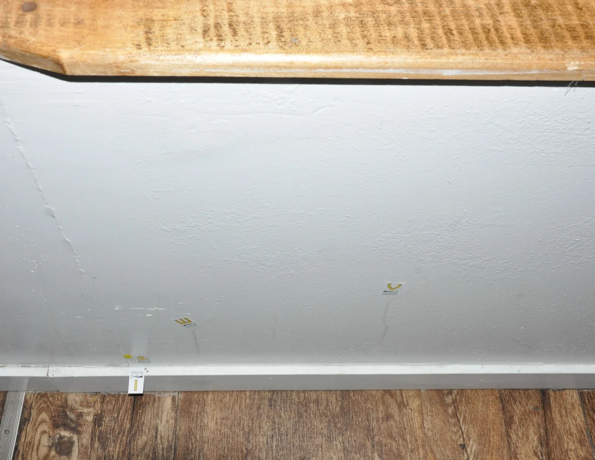 Half-wall beneath a wooden cap with small labels and faint vertical streaks.