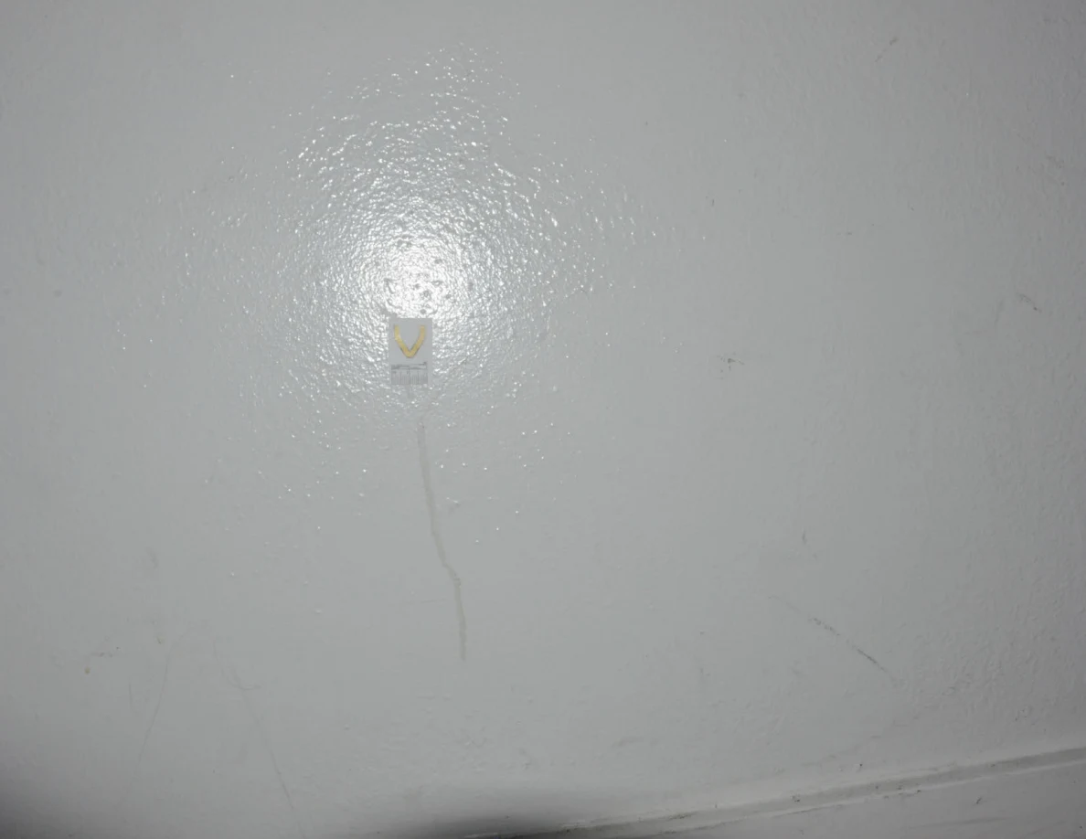 Label V beside a faint vertical streak and other light scuffs on a pale wall.