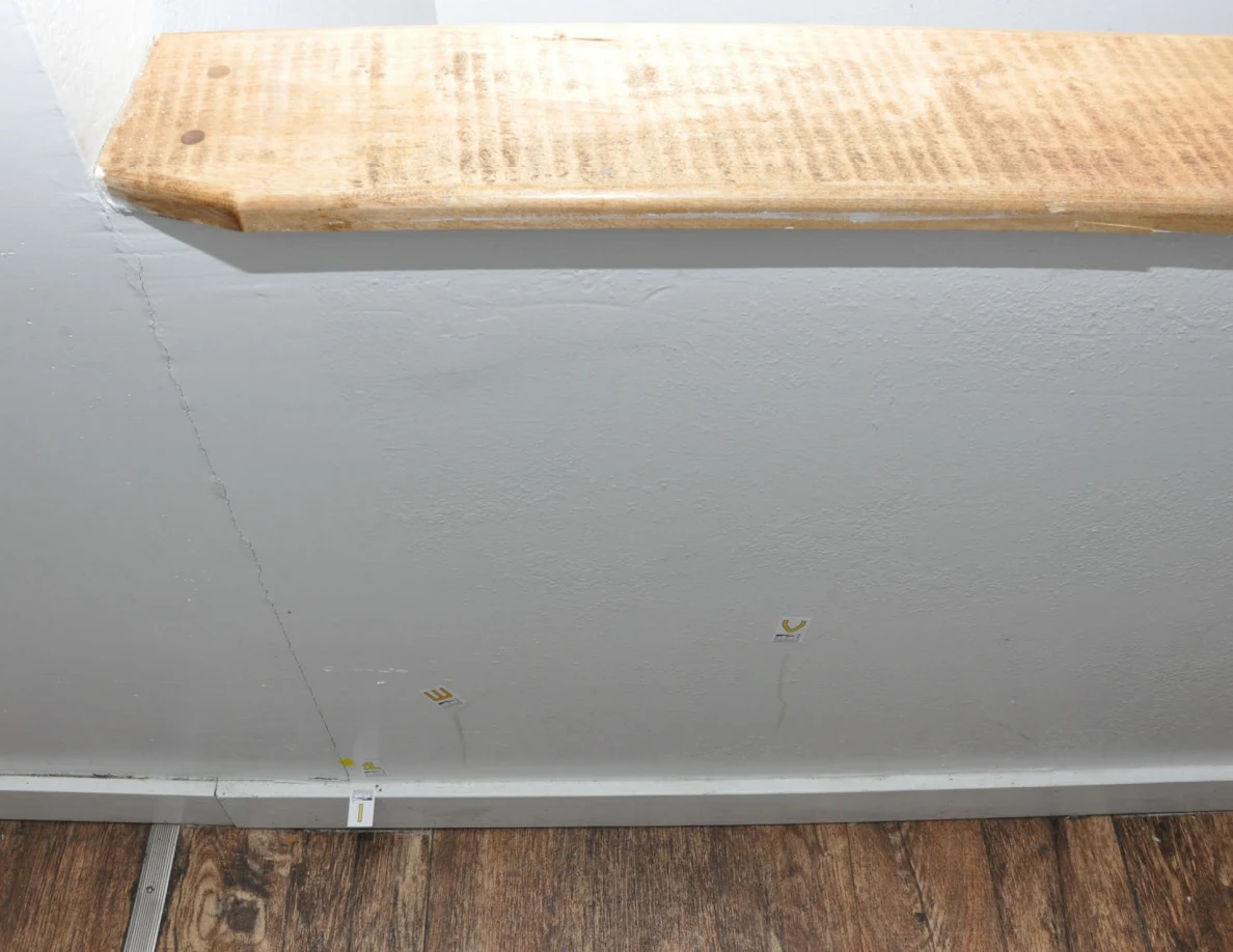 Wood-capped half-wall with labeled faint streaks and a crack extending toward the baseboard.