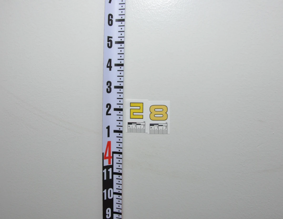 Close view of label 28, a measuring rod and a faint curved scuff on pale paint.