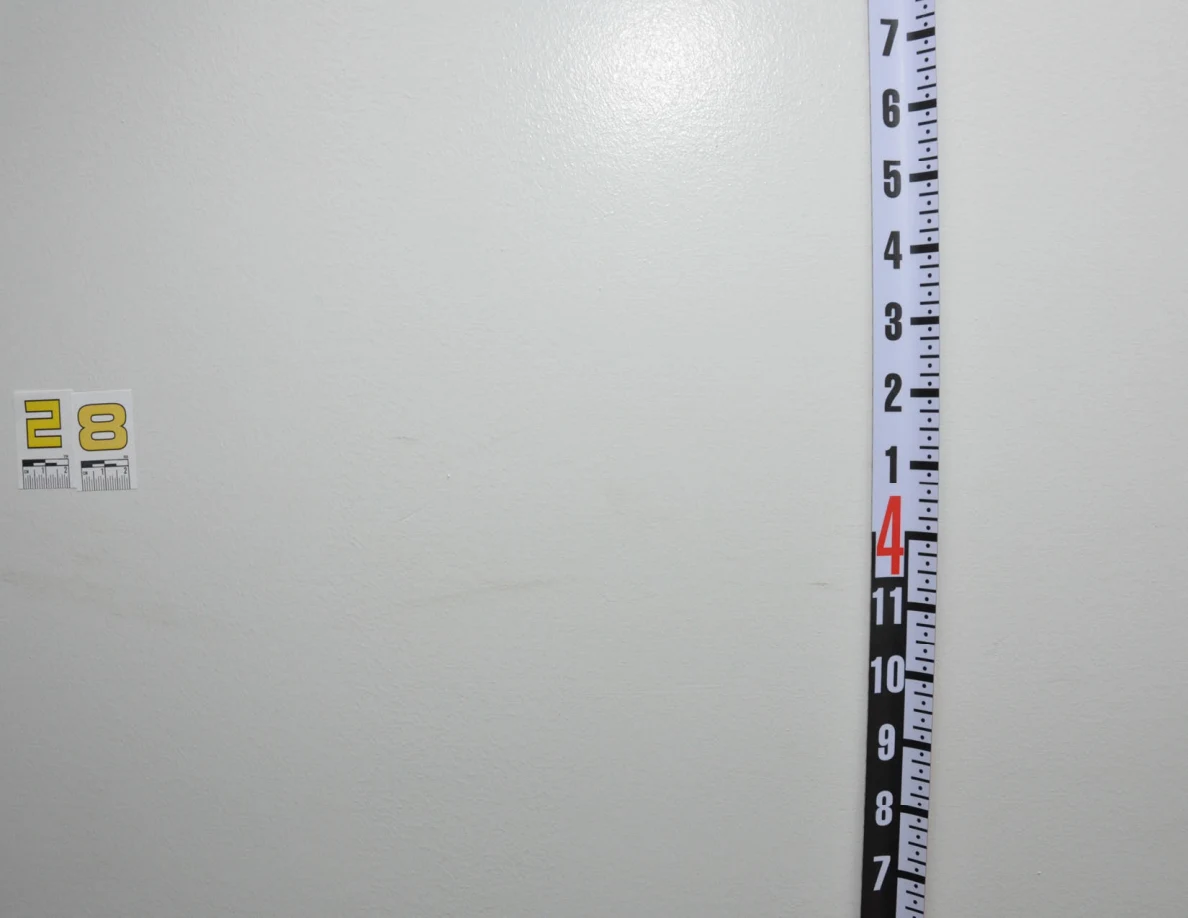 Wider view of label 28 and a vertical measuring rod across a faint curved wall scuff.