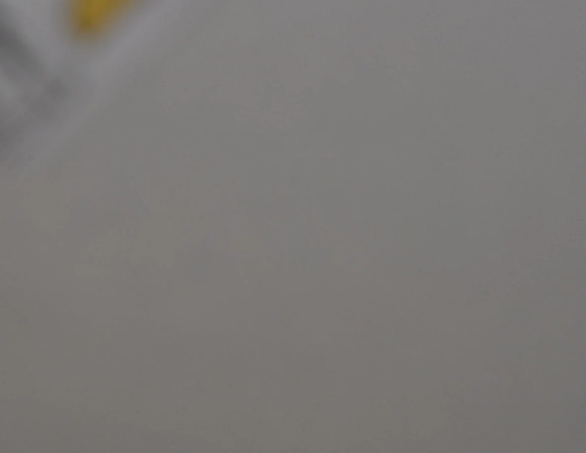 Out-of-focus close view of a pale wall beside a cropped yellow label.