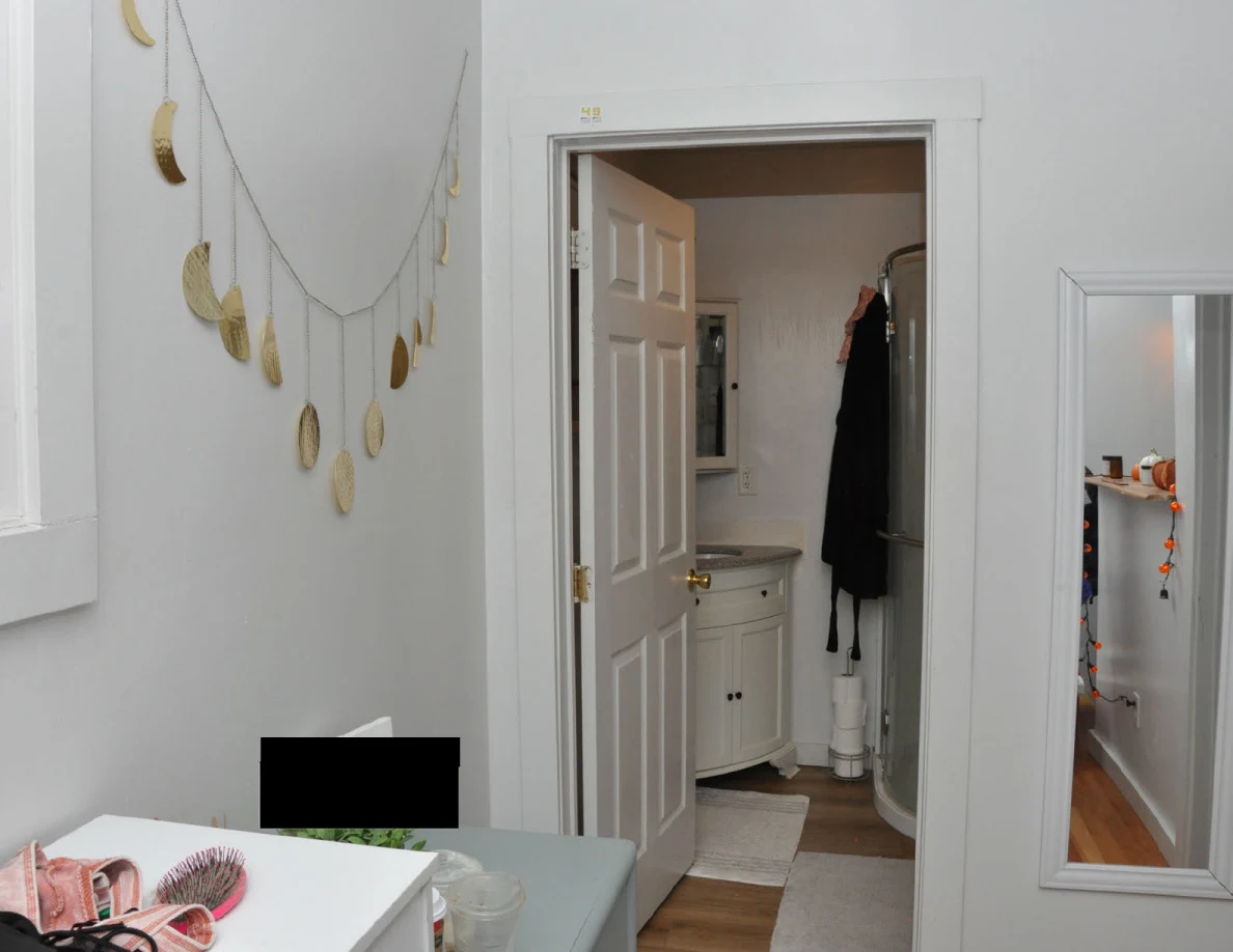 Bathroom doorway with a vanity, curved shower enclosure, hanging dark garment, wall mirror and moon-shaped decorations.