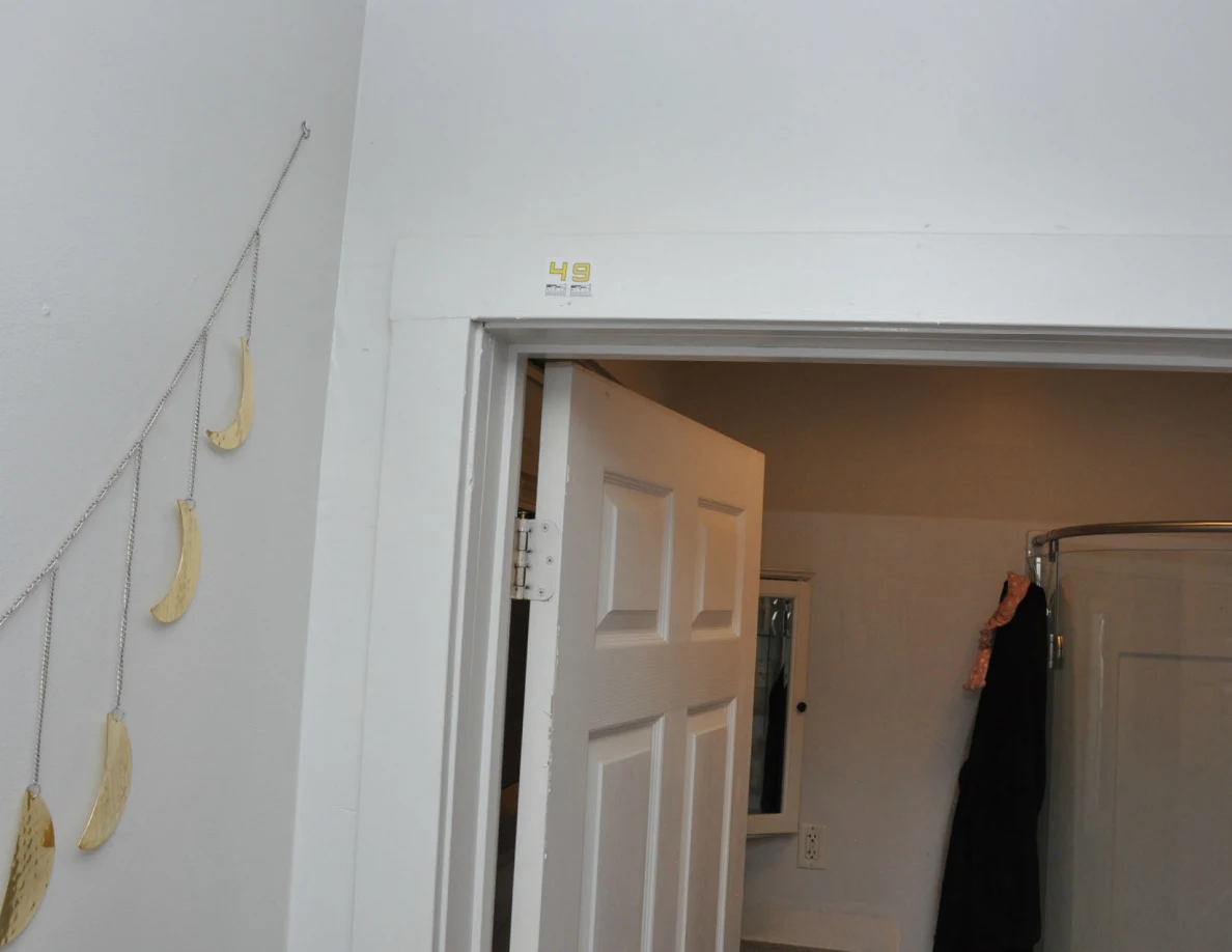 Label 49 above an open bathroom door beside hanging moon-shaped wall decorations.
