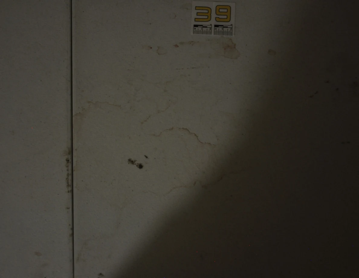 Darkened view of label 39, a table seam and irregular rings on a white tabletop.