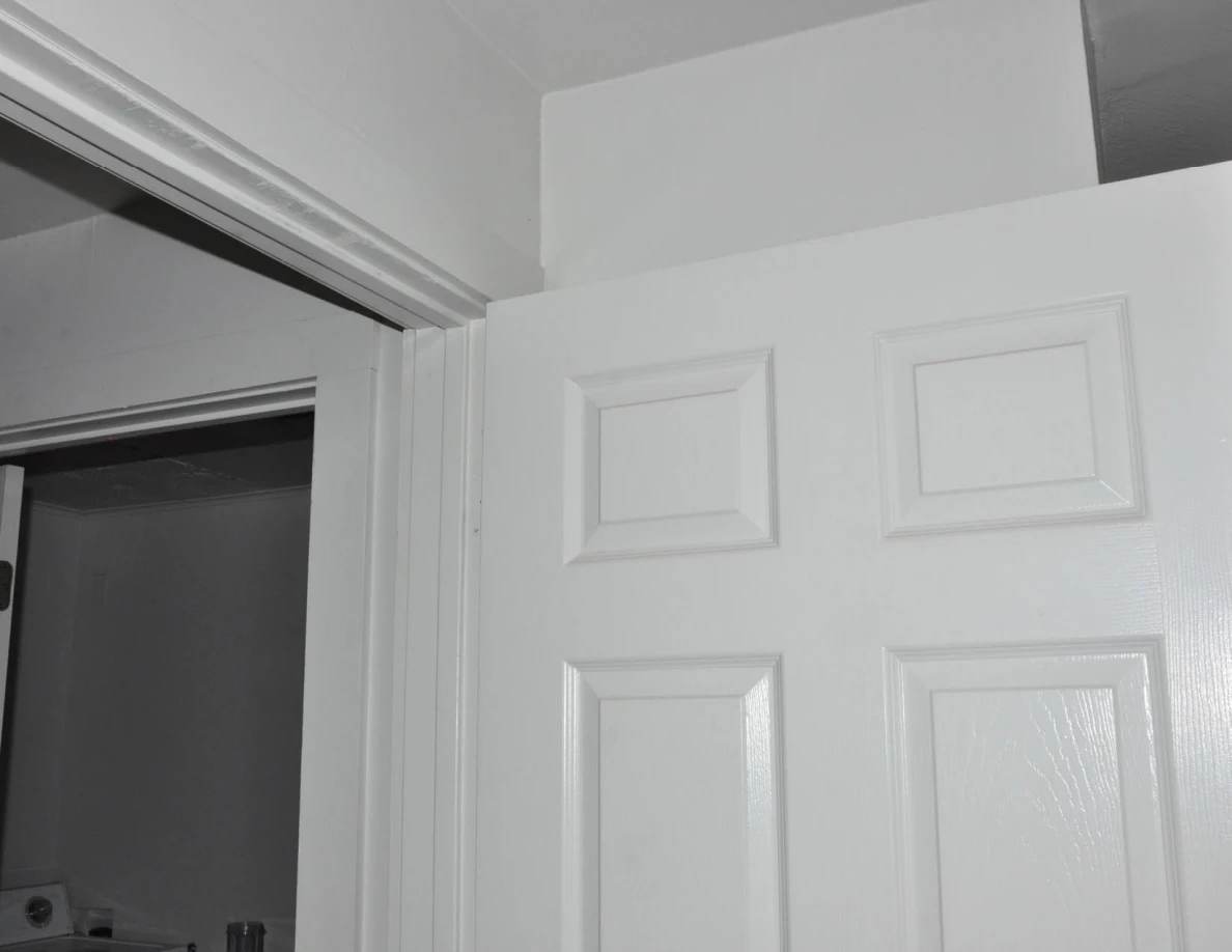 Upper part of an open white paneled bathroom door and frame.