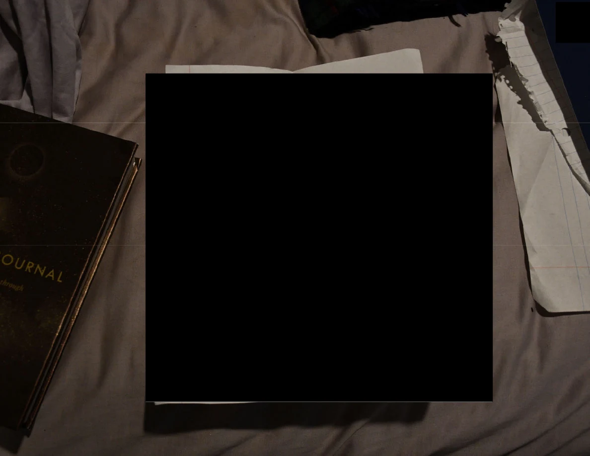 Close view of redacted papers on bedding beside a partially visible journal.