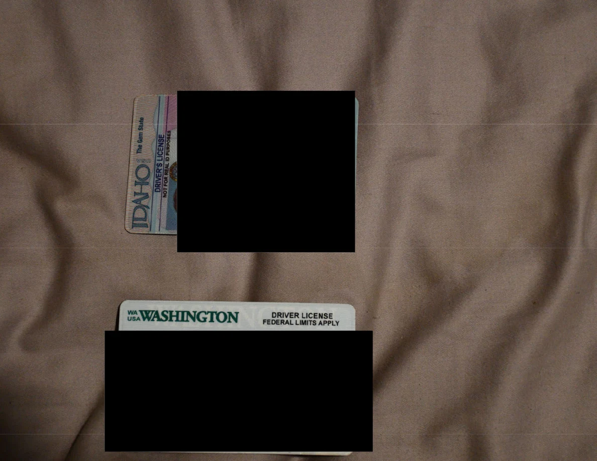 Idaho and Washington identification cards on bedding with personal details blacked out.