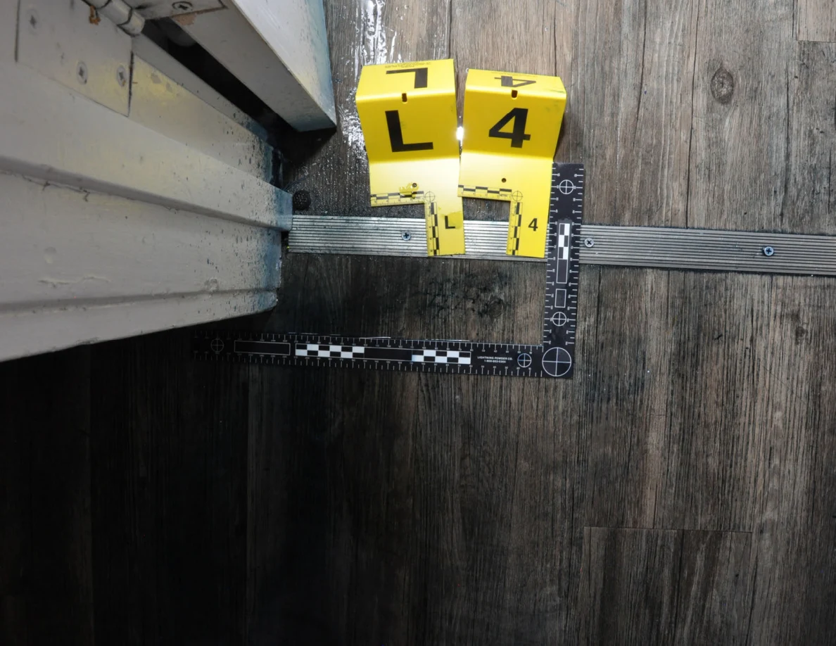 Closer view of markers L and 4, a metal threshold and dark floor marks within a measuring scale.