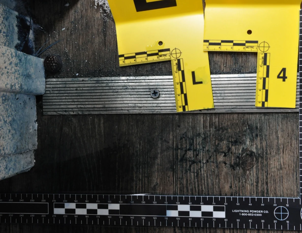 Close view of a metal threshold with markers L and 4 above dark patterned floor marks.