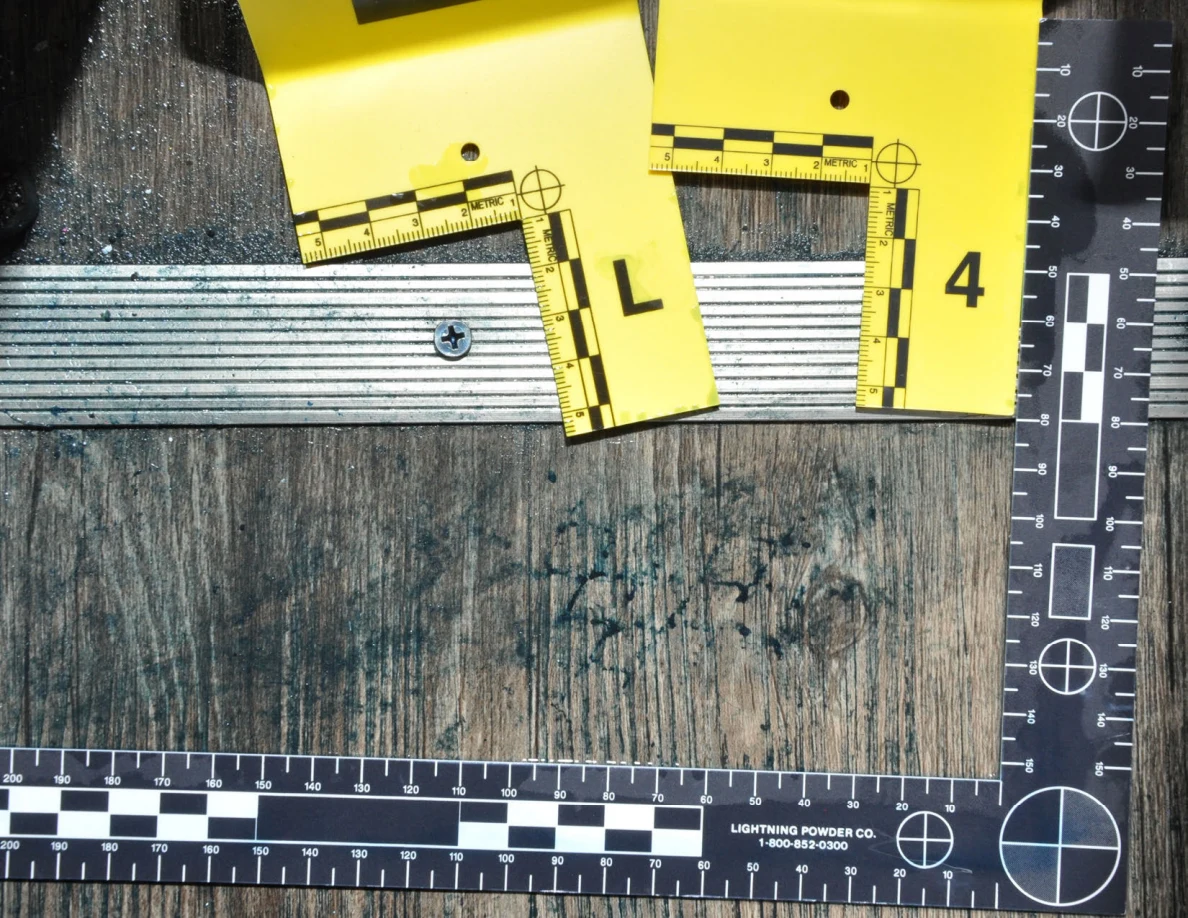 Dark patterned marks on wood-pattern flooring beside threshold markers L and 4 and a black measuring scale.