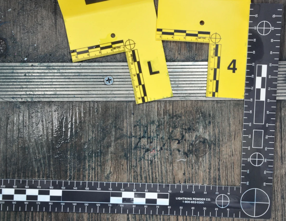 Angled close view of dark floor marks below a metal threshold with markers L and 4.