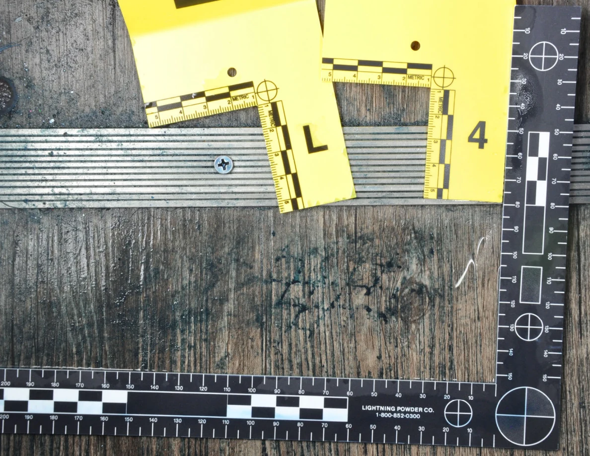 Close view of dark patterned floor marks beside yellow markers and a small pale strand.