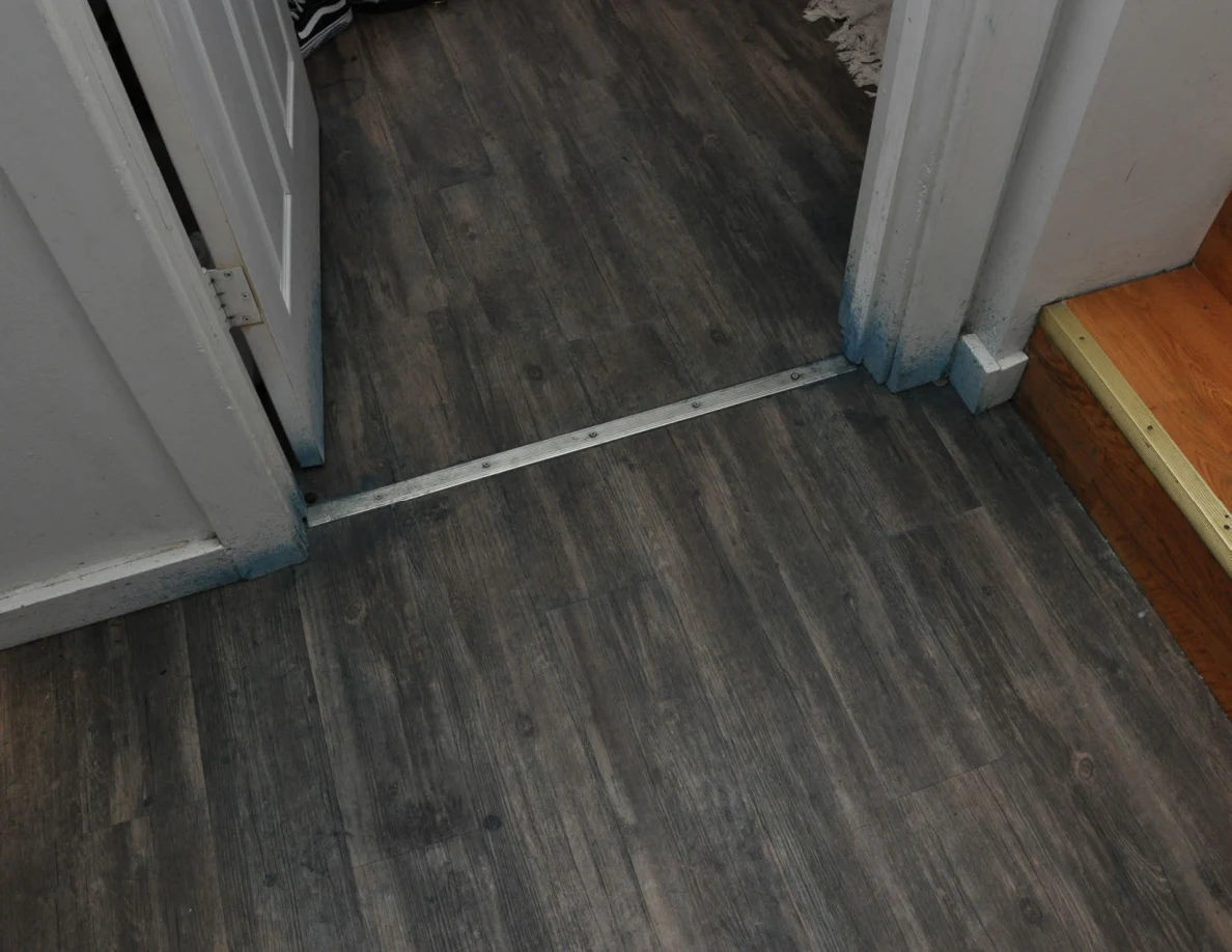 Bedroom threshold with blue marks near the base of white trim and a wooden stair at the right.