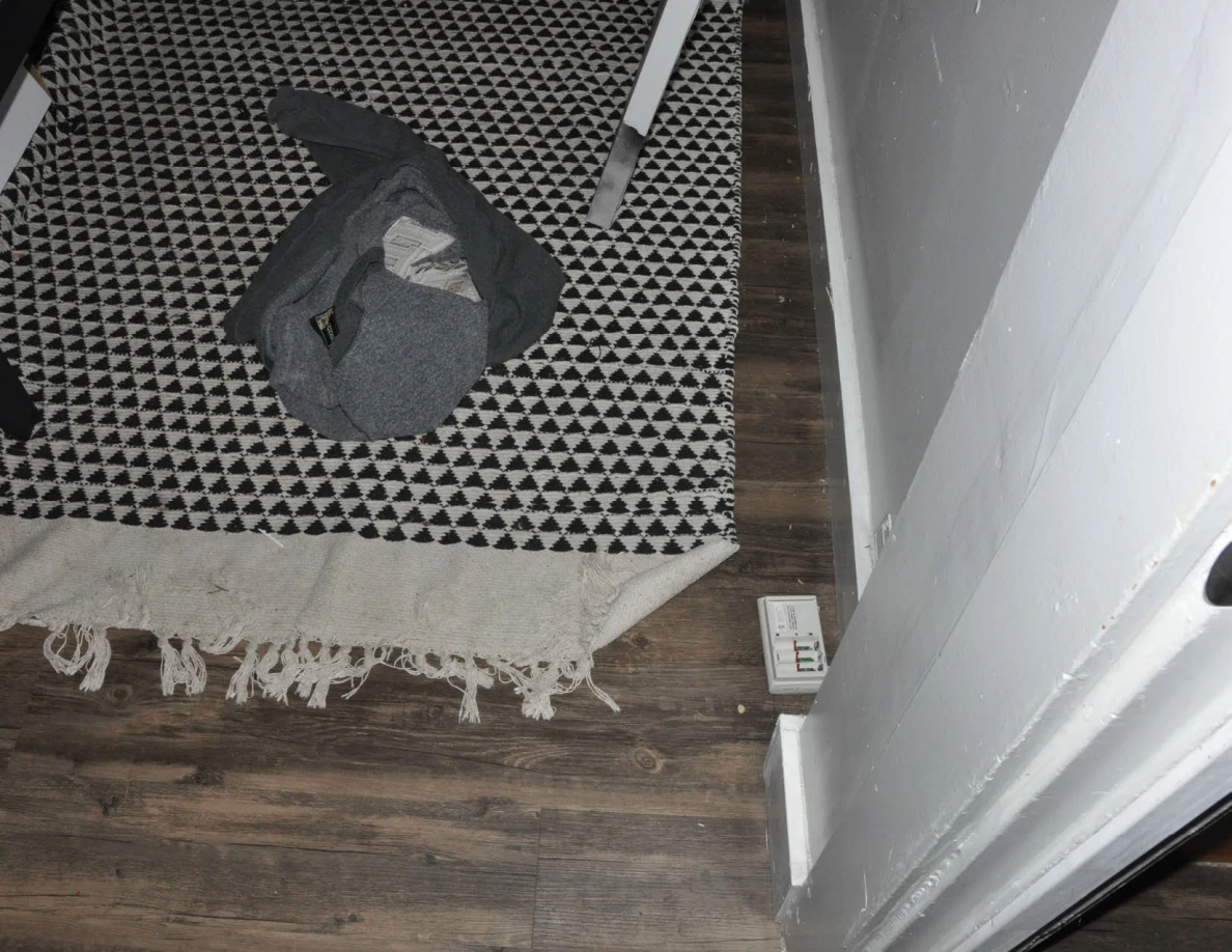 Gray garment on a black-and-white patterned rug near a door frame.