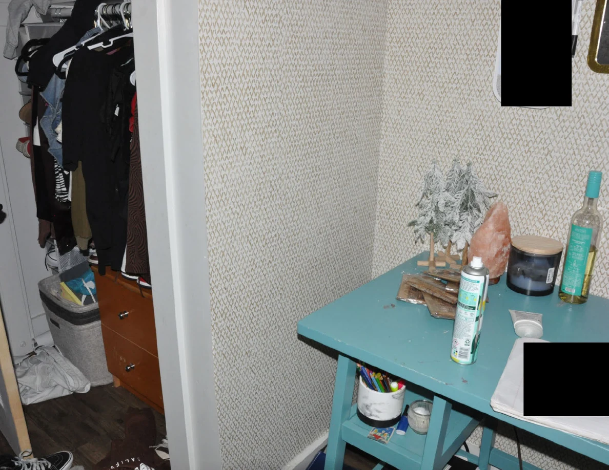 Turquoise desk beside an open closet with hanging clothing, drawers and floor items.